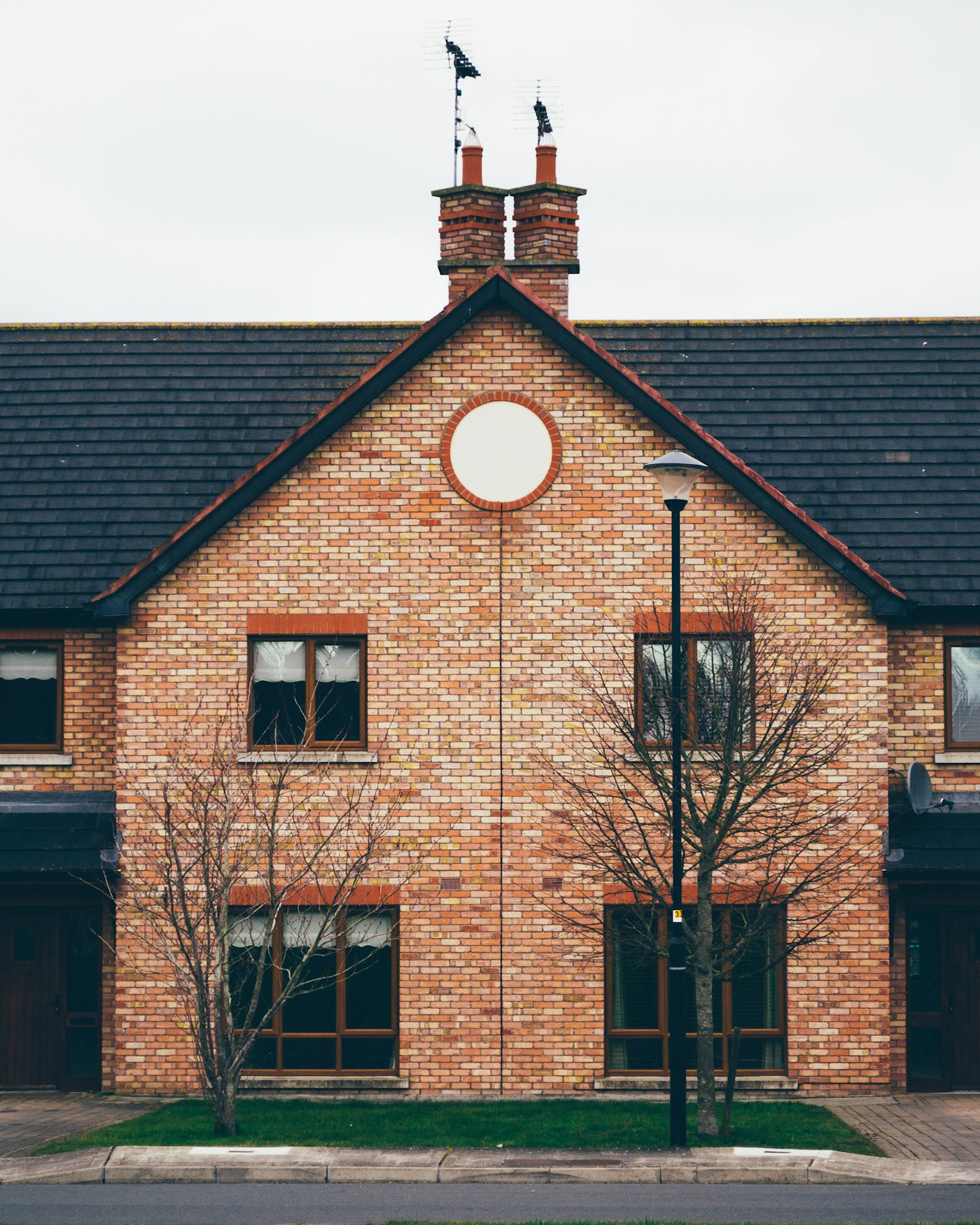 Pair of brick-built semi-detached homes with chimneys on a residential street